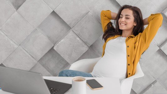 smiley pregnant woman looking her laptop