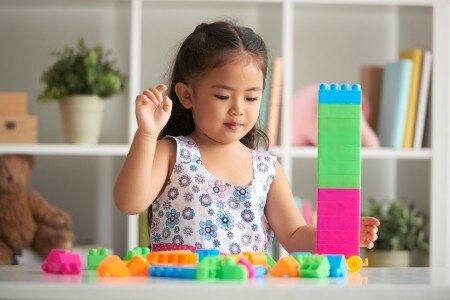 Small asian girl playing with duplo